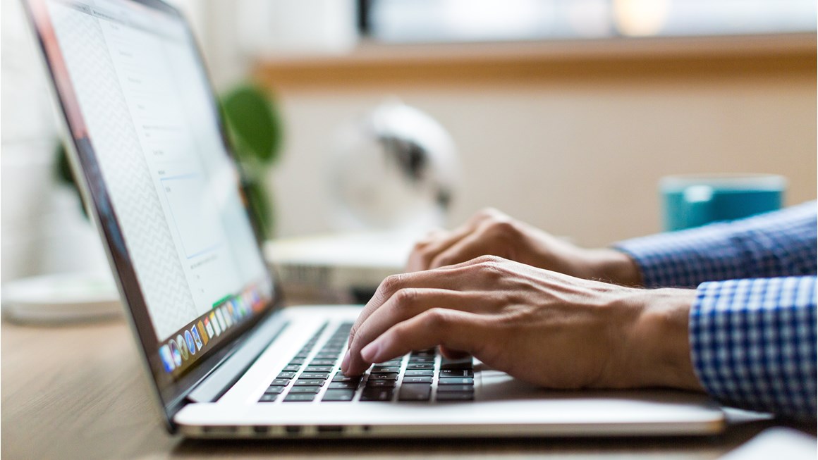 Close up of hands on a laptop keyboard at a desk