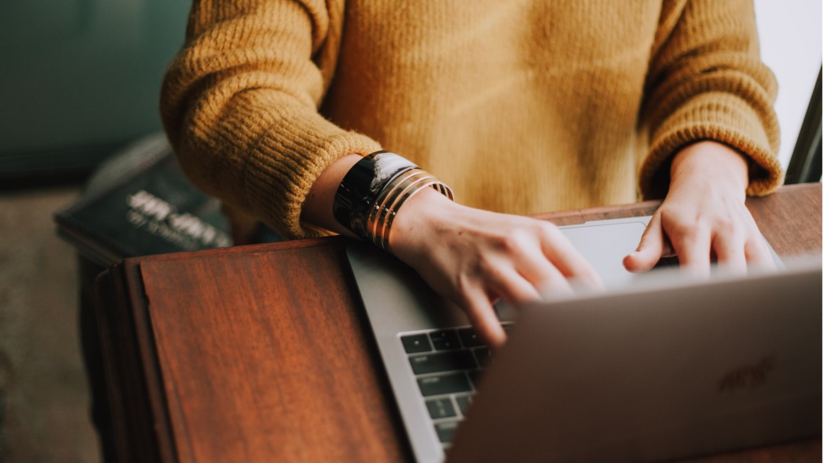 Close up of person using a laptop keyboard while sitting at a desk